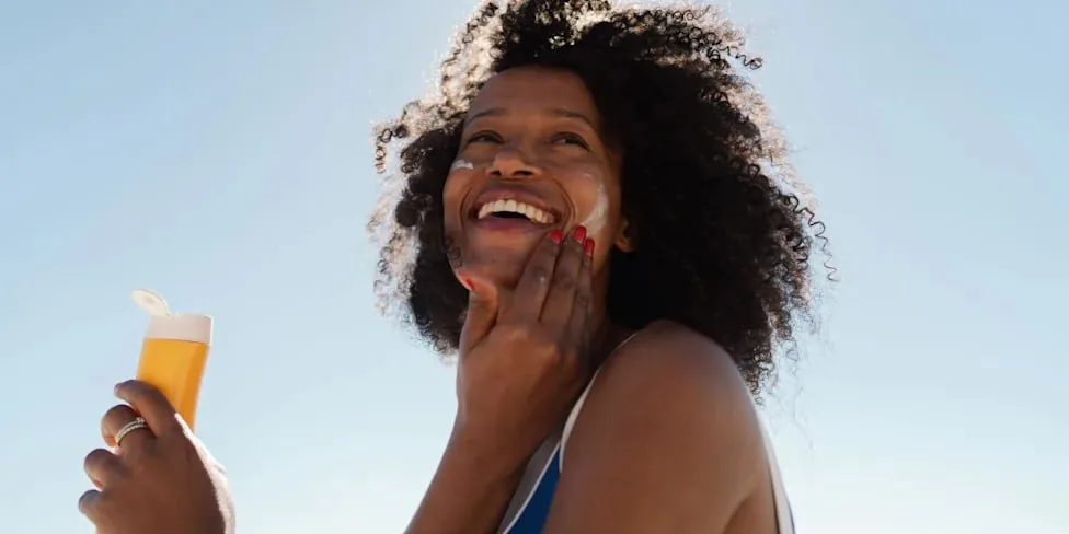 Woman applying sunscreen outdoors, sun protection in action